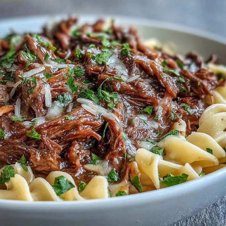 Crockpot French Onion Pot Roast Pasta servido con queso Gruyère derretido y perejil fresco sobre fideos mantequilla