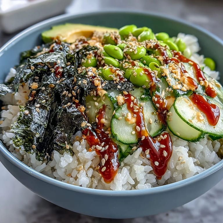 3. Delicious seaweed snack sushi bowl with julienned veggies, avocado slices, nori strips, and a creamy, spicy sauce, perfect for sushi lovers.