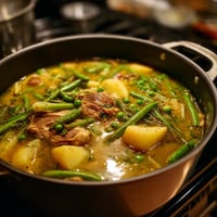 Una cacerola llena de carne de cerdo y verduras, incluyendo garbanzos.