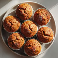 A plate of muffins with powdered sugar on top.