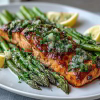 Delicioso salmón al horno con espárragos en salsa de mantequilla de ajo, perfecto para una cena primaveral elegante y saludable.