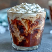 Café frío con crema dulce de vainilla servido en vaso helado.